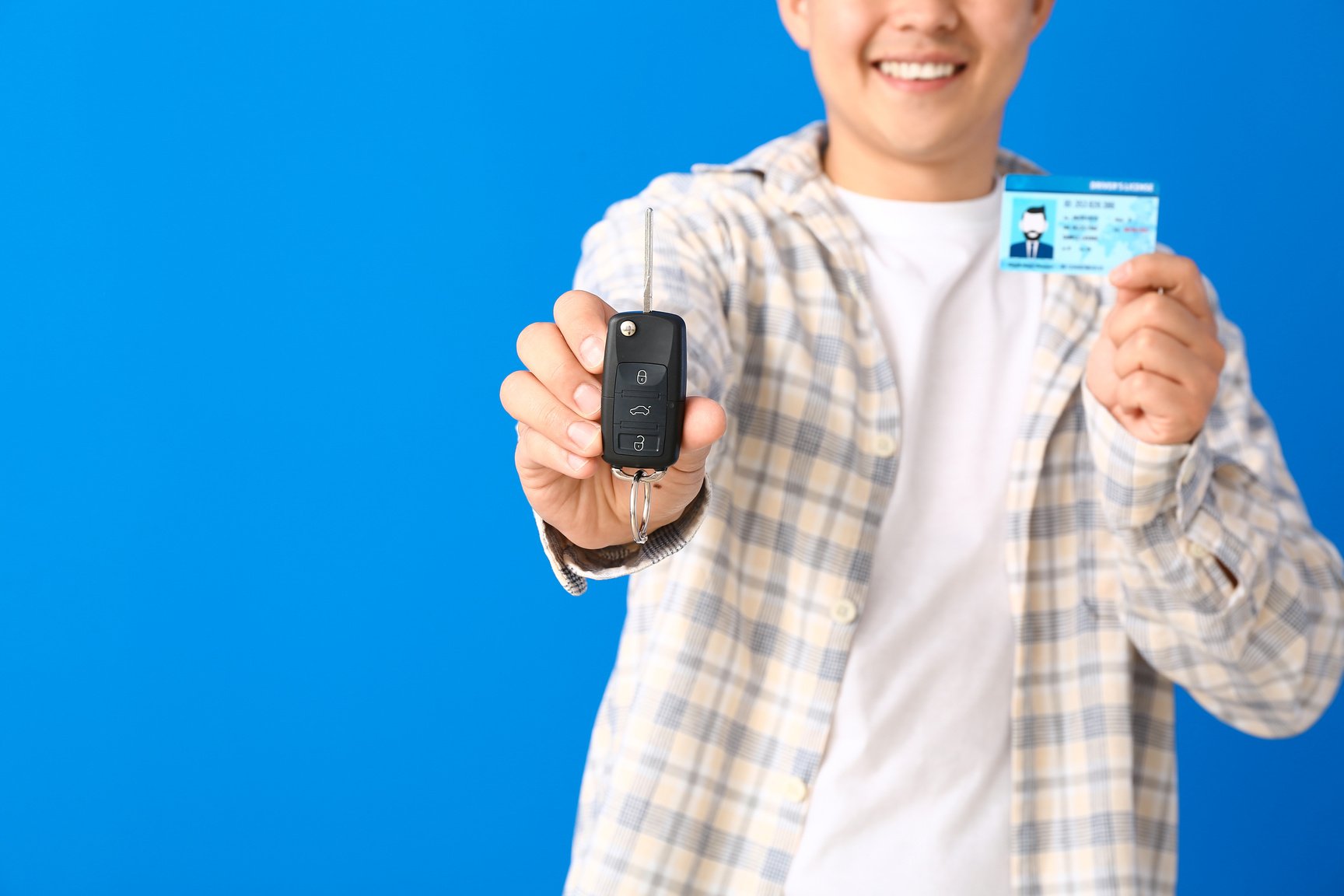 Person with Car Key and Driving License on Blue Background