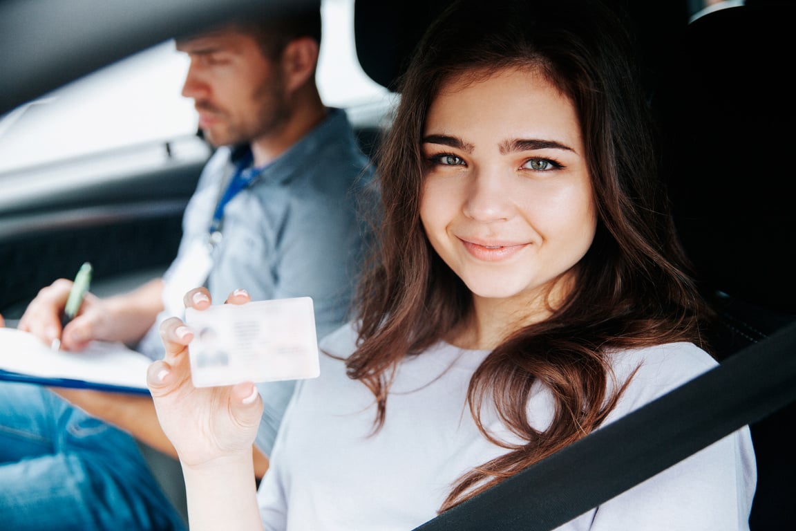 Attractive young woman showing driver's licence, looking at